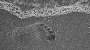 footprint in sand with wave coming near